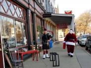 Downtown shopping sidewalk Santa Clause walking away and bagpiper playig