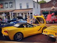 Yellow Corvette and other classic cars parked on the brick street